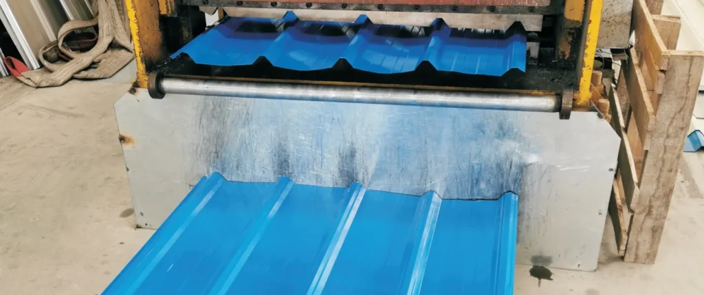 Blue color-coated trapezoidal roof panel coming off a roll forming machine